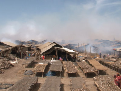 Smoke envelopes the vast fish smoking area so as to obscure the other end of the village